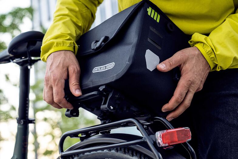 Durch einfaches Herunterdrücken eines Flügels des «Top-Lock-Systems» und seitliches Kippen der Tasche ist das Gepäck in Sekundenschnelle gelöst. Taschensystem von Ortlieb. Foto: www.ortlieb.com / pd-f