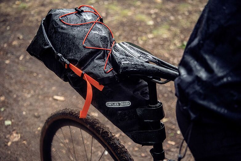 In einer Bikepacking-Satteltasche von Ortlieb lässt sich viel Gepäck unterbringen. Zudem schützt sie den Rücken vor emporgeschleudertem Dreck und Nässe. Praktisch: Die Kordelspinne hält zum Beispiel die Regenjacke griffbereit. Foto: www.ortlieb.com / pd-f